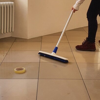 Plastic broom with synthetic bristles on tiled floor.
