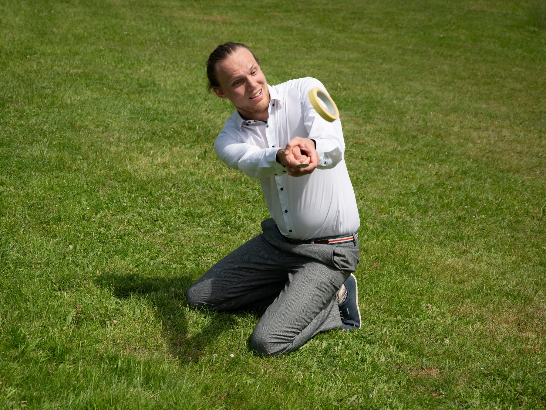 Person kneeling on the lawn with a Spoon in a horizontal position after lifting a Quibble into the air