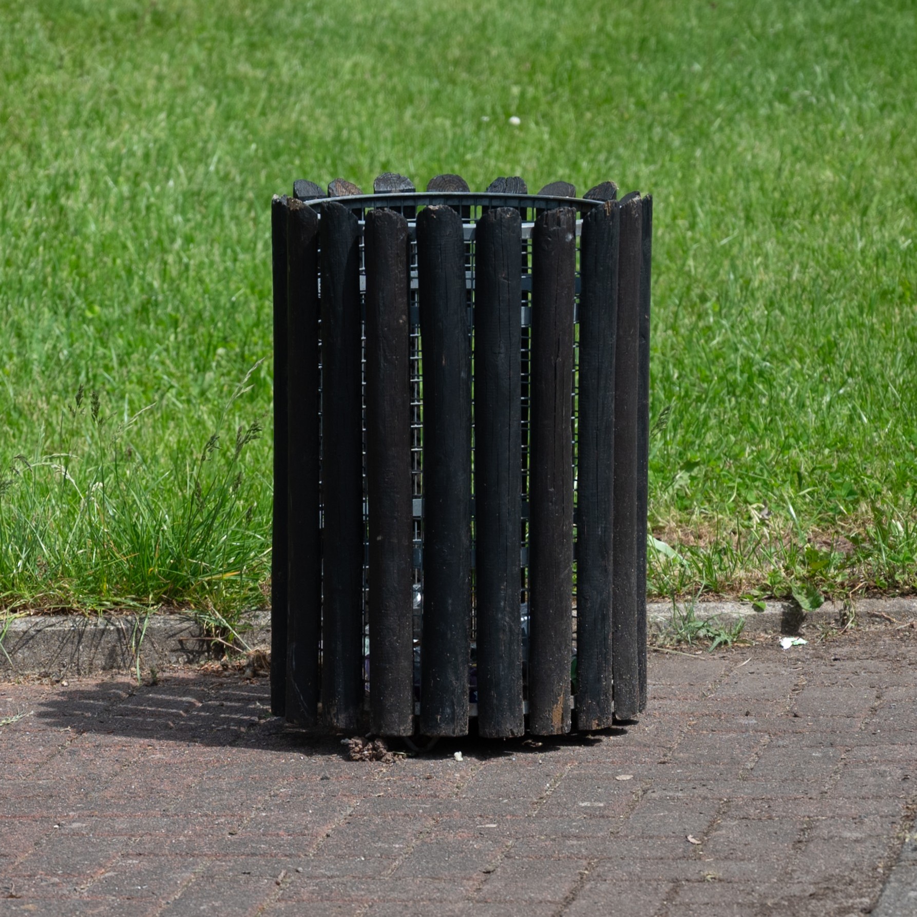 Quiver, here a wooden cylinder with steel framing inside an open top next to a lawn