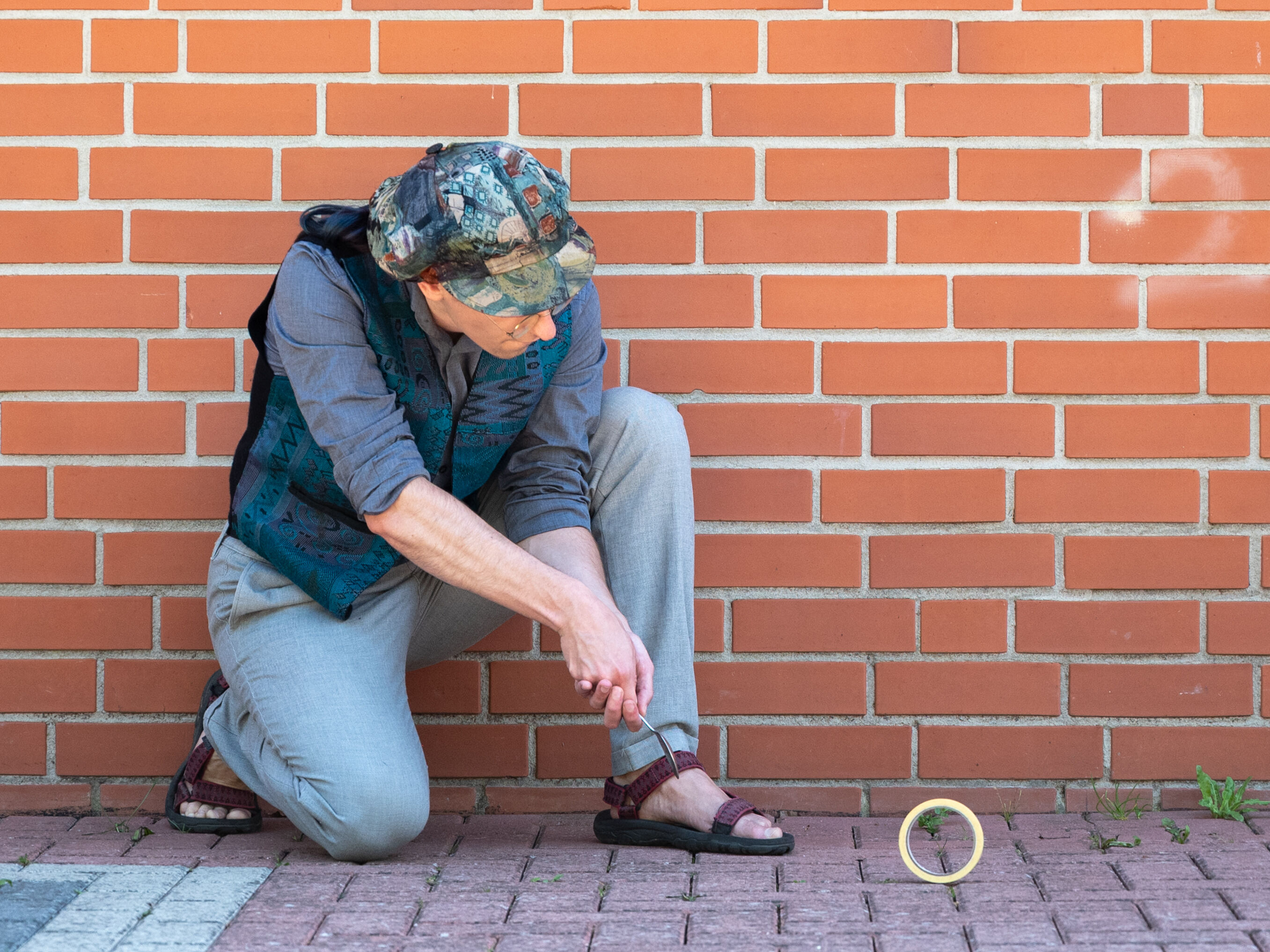Person kneeling with one foot on the pavement after hitting an upright Quibble rolling along the brick pavement.